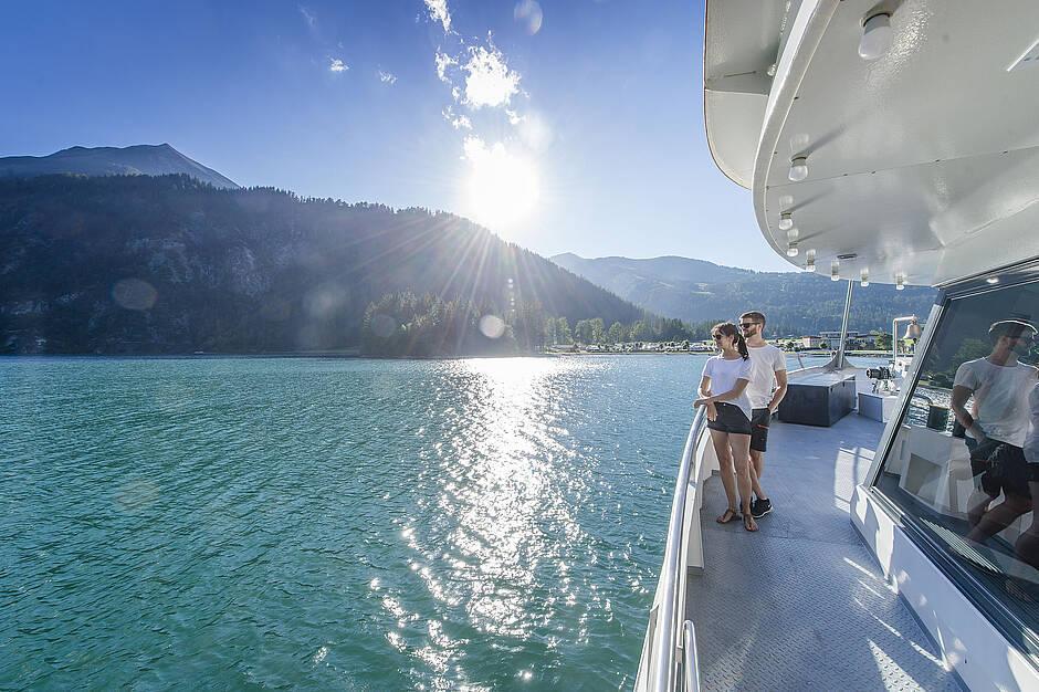 Ein Paar verbringt den Sommerurlaub in Tirol auf dem türkisfarbenden Wasser des Achensees bei einer Schifffahrt mit dem Achenseeschiff